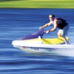 Man speeding along a lake on a jet ski